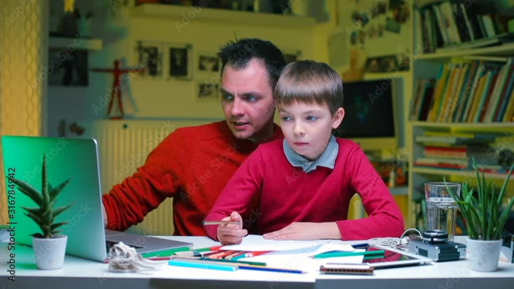 Father and son are doing assignments while sitting at the table. Father and son are doing assignments while sitting at the table.