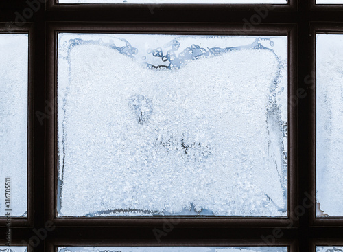 Frost patterns on window glass framed with dark wood