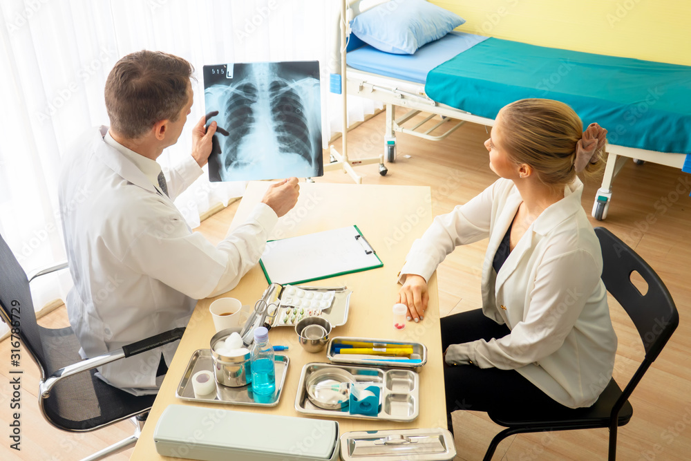 Doctor explaining lungs x-ray to women patient in clinic or Doctor in the office examining an x-ray and discussing with a patient Doctor explaining lungs x-ray to women patient in clinic or Doctor in the office examining an x-ray and discussing with a patient