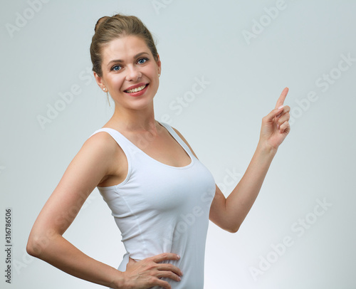 smiling woman in white vest pointing up with finfer.