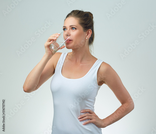 sporty woman in white casual vest drinking water from glass. © Yuriy Shevtsov