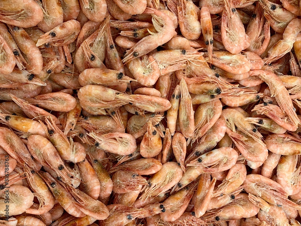 Background texture: a lot of frozen shrimp. Little pink prawns in a store in the fridge.