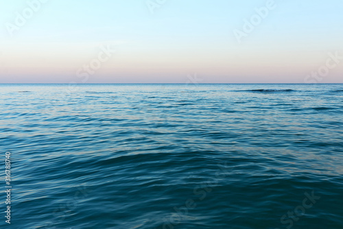 Wide horizon of sea and sky. Sunset seascape. Calm open sea ocean. Sunset evening time. Soft focus  motion blur.