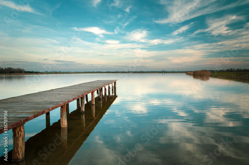 Long wooden bridge on the lake  horizon and white clouds on blue sky in Staw  Poland