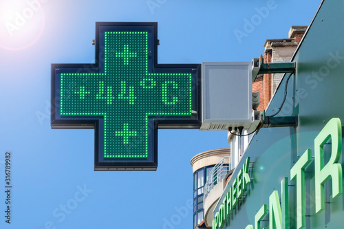 Thermometer in green pharmacy screen sign displays extremely hot temperature of 44 degrees Celsius during heatwave in summer photo