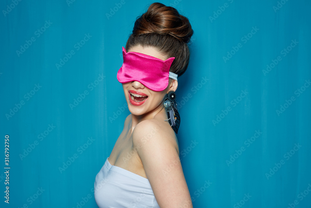 Smiling girl with dental braces wearing pink eye mask.
