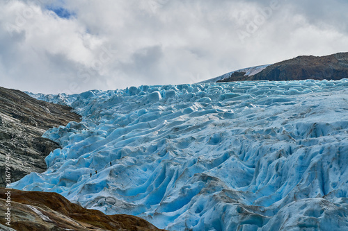 svartisen glacier in norway with huge ice blocks and three little mountaineers 