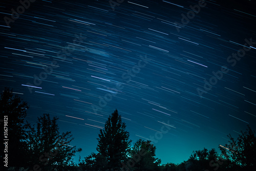 Colorful startrails above dark grim forest