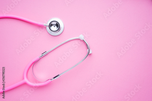 Women in the healthcare industy concept. A pink strethoscope on a pink background.