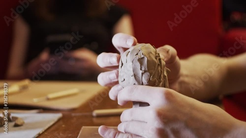 Young artist sculpting bust of woman from real young woman using Plasticine (non-drying clay)
