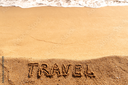 Vacation concept on the beach. Word Travel written on the sand near the sea. Copy space