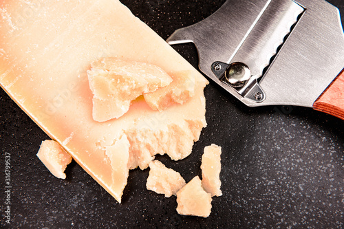 Closeup pieces parmesan cheese on black plate stone with knife