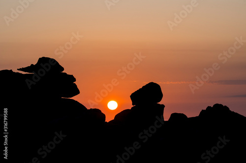 Strange rock formations silhouetted against sunrise along the Côte de granit rose / Pink Granite Coast, Côtes d'Armor, Brittany, France