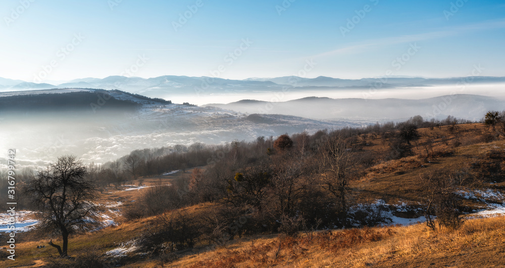 Early spring mountain landscape panorama with fog and low clouds 