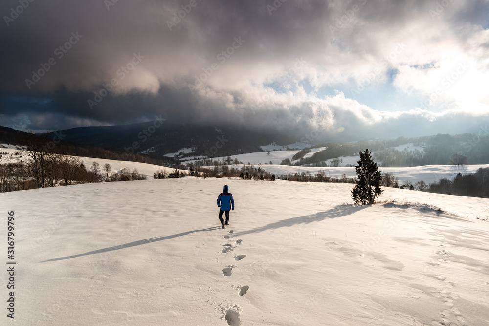 Adventure Man Walk in Deep Snow in Mountains at Winter Season at Sunrise