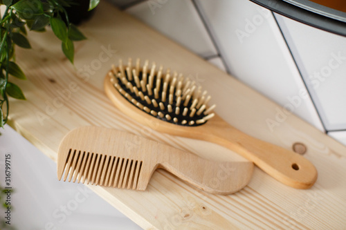 Spa and bath cosmetics, basket with towel rolls in rustic interior. Natural materials in bathroom. Wooden hair brush. Bamboo comb on the dressing table. Eco-friendly hair care products. Natural beauty photo