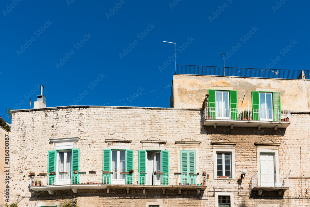 white apartments with balcony and green wooden shutters. Molfetta, Italy
