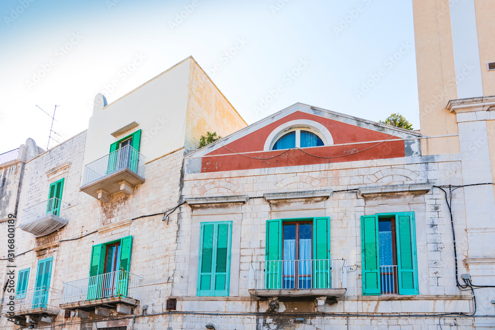 White apartments with balcony and green shutters. Molfetta, Italy