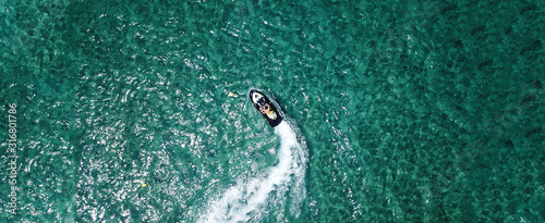 Aerial drone ultra wide photo of jet ski couple cruising in high speed in tropical exotic bay with emerald sea © aerial-drone
