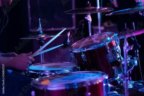 Artistic man playing on professional drum set on the stage