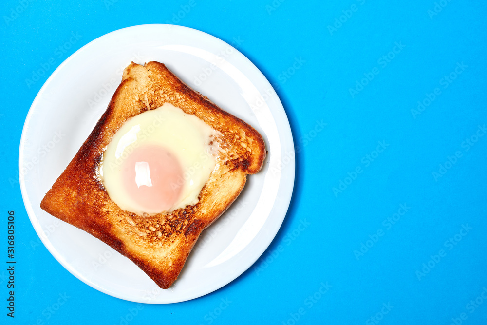 Toast with an egg on a plate on a blue background. Toast with an egg on a plate on a blue background.