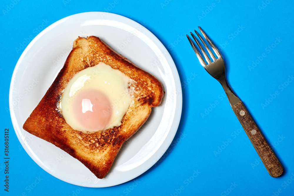Toast with an egg on a plate on a blue background. Toast with an egg on a plate on a blue background.