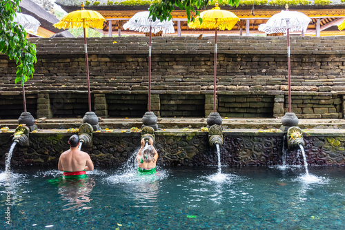 Unidentified man and woman praying and doing purification ritual at the holy spring water at Pura Tirta Empul temple. photo