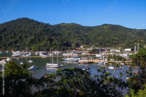 many boats and yachts anchored in a cozy bay among the lush tropical vegetation against the backdrop of the mountains. Rich luxury yachts in the bay