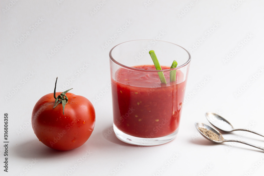 glass of natural fresh tomato juice with green onion strow, salt and pepper in spoons on white background glass of natural fresh tomato juice with green onion strow, salt and pepper in spoons on white background