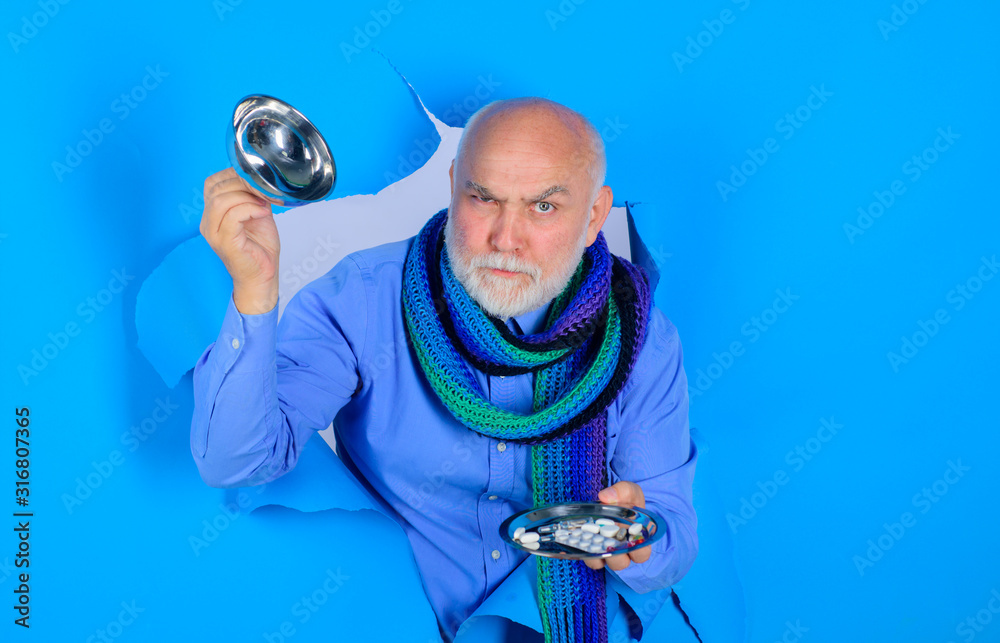 Fototapeta premium Bearded man holds different pills on plate. Medicine, treatments and healthcare. Man hands with pills. Man through hole holds different pills. Medicine pills on plate. Tablets in hand of patient.