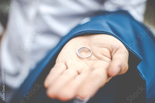 Close-up the Groom holding wedding ring on the palm. © Oranuch