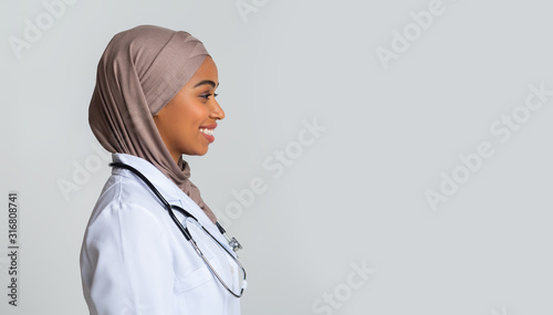 Photography Afro muslim female doctor in hijab and lab coat, profile portrait