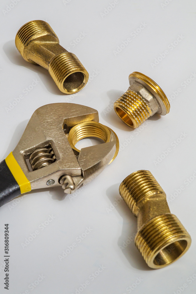 Set of brass fittings and tool is often used for water and gas installations on gray background Set of brass fittings and tool is often used for water and gas installations on gray background