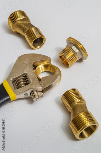 Set of brass fittings and tool is often used for water and gas installations on gray background