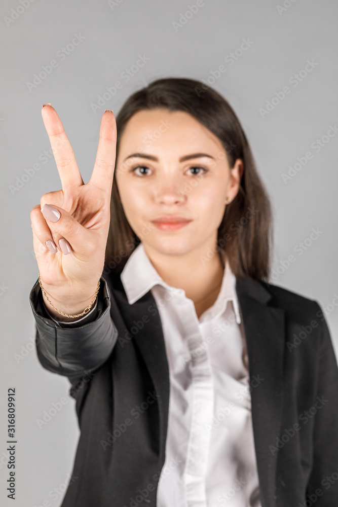 girl in black jacket on grey background showing 2 fingers girl in black jacket on grey background showing 2 fingers