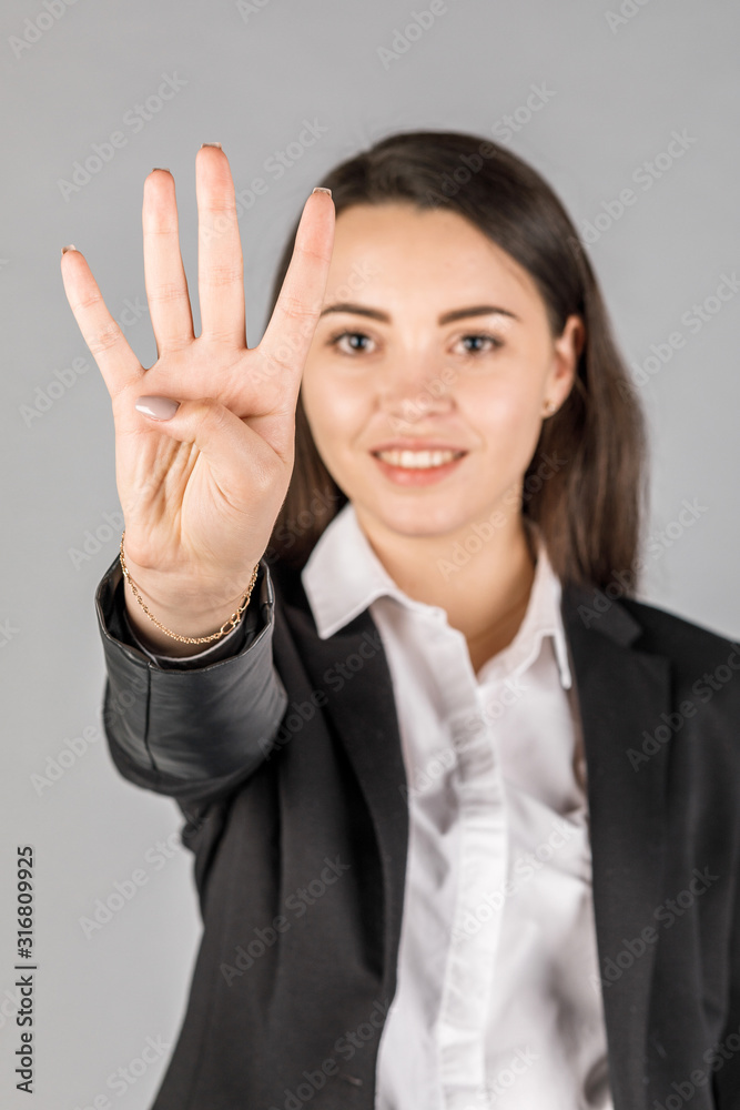 girl in black jacket on grey background showing 4 fingers girl in black jacket on grey background showing 4 fingers