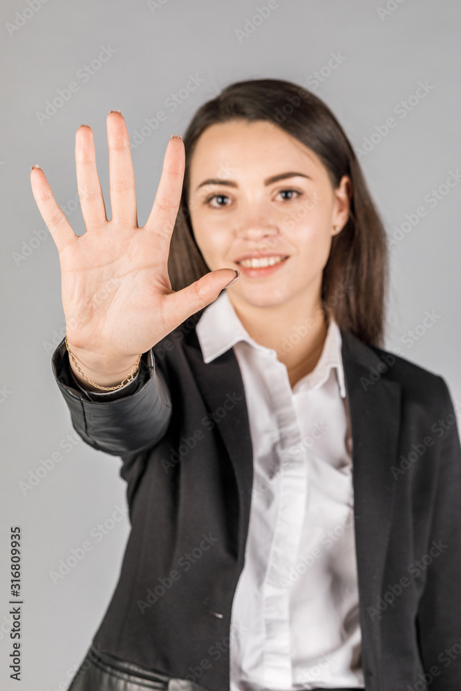 girl in black jacket on grey background showing 5 fingers girl in black jacket on grey background showing 5 fingers
