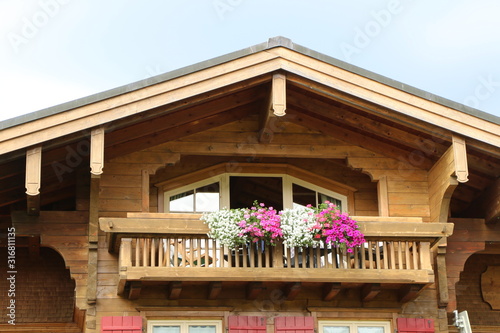 Alpenländische Architektur, Holzbalkon in Österreich mit Sommerblumen