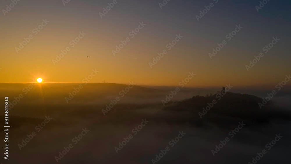 beautiful sunrise over the fog with a view of the castle ruins in the Bavarian forest 