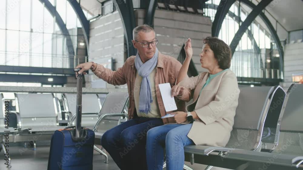 Portrait of cheerful elderly couple sitting in waiting area and waiting for their flight boarding Portrait of cheerful elderly couple sitting in waiting area and waiting for their flight boarding