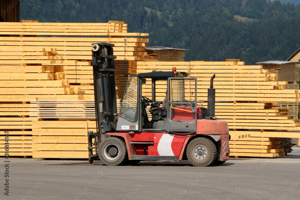Gabelstapler vor gestapeltem Holz in einem Sägewerk