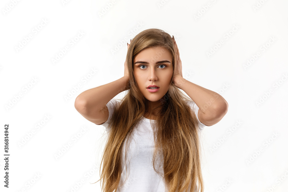 Portrait of young beautiful woman closes her ears with hand on white background Portrait of young beautiful woman closes her ears with hand on white background