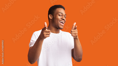Happy afro guy choosing you over orange background photo