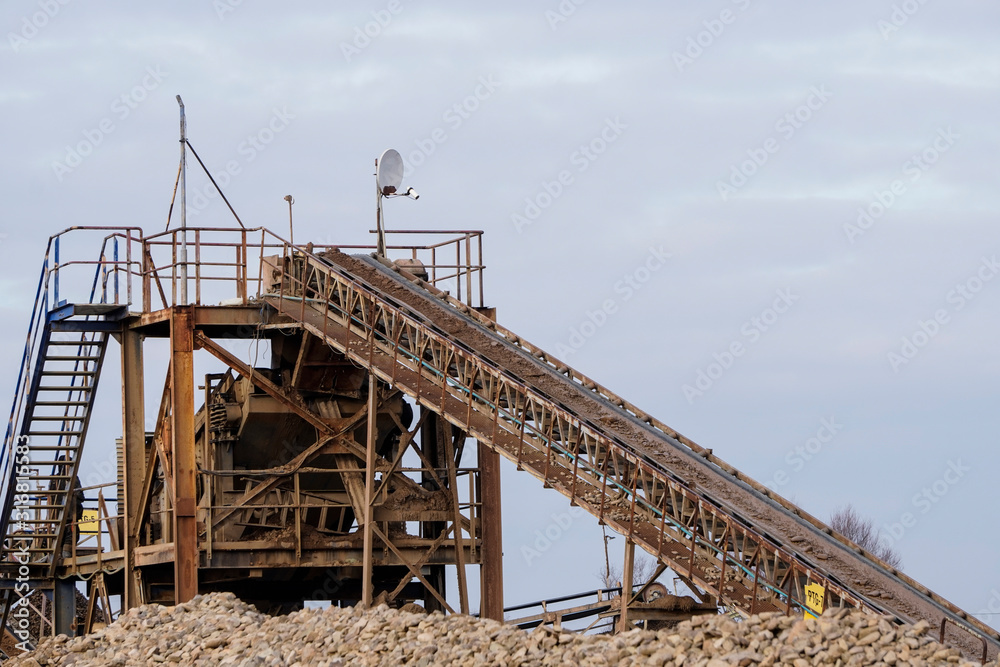 Loading stones and sand onto the conveyor belt of the sorting plant. Machine for crushing stone. Conveyor belt of heavy machinery loads stones and gravel. Industrial background