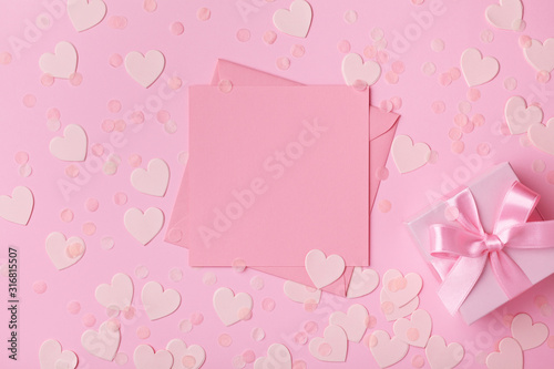 Pink background with gift or present box and paper hearts. Greeting card for Valentines, Woman or Mothers Day. Flat lay style. © juliasudnitskaya