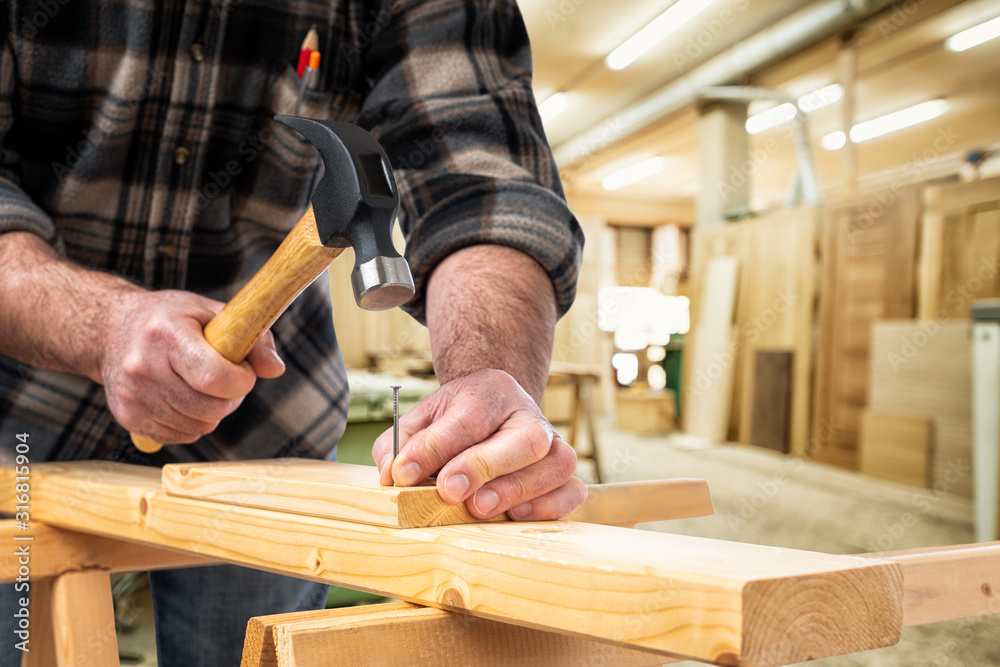 Close-up. Carpenter with hammer and nails fixes a wooden board. Construction industry, carpentry workshop. Close-up. Carpenter with hammer and nails fixes a wooden board. Construction industry, carpentry workshop.