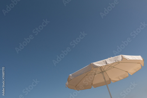 Big white parasol in front of a sunny blue sky