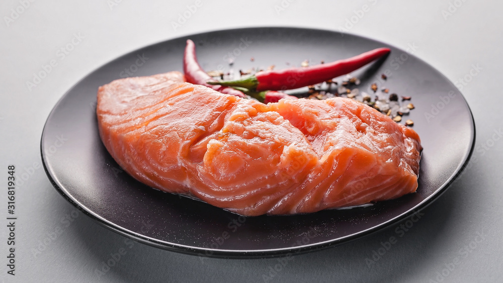 Food banner. Fresh salmon slice, herbs, spices and hot peppers on a dark plate.
