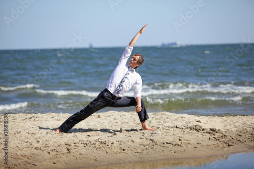 Caucasian business man practicing yoga on the beach