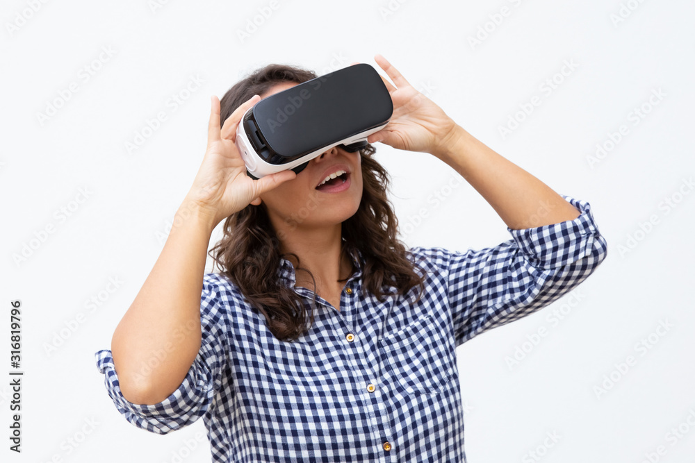 Young woman using VR headset. Attractive young woman in virtual reality headset moving hands on white background. Technology concept Young woman using VR headset. Attractive young woman in virtual reality headset moving hands on white background. Technology concept